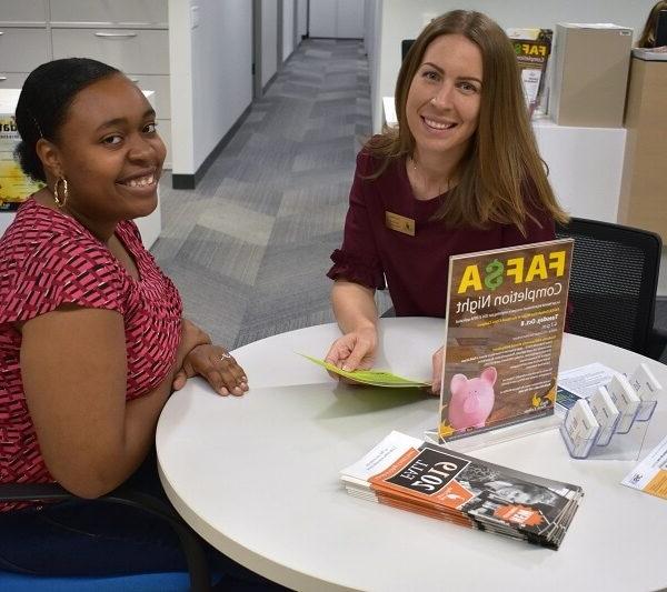 Financial aid director and student sitting at a table smiling